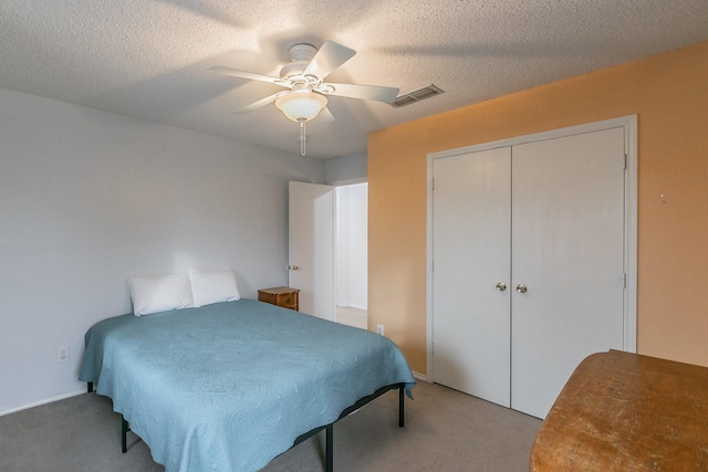 carpeted bedroom with ceiling fan, a textured ceiling, and a closet