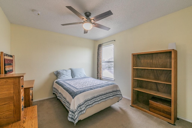 bedroom with ceiling fan, carpet floors, and a textured ceiling