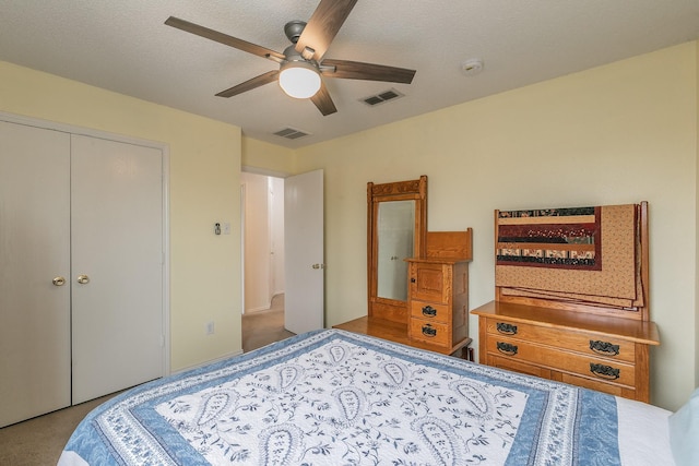 bedroom with ceiling fan, a textured ceiling, light carpet, and a closet