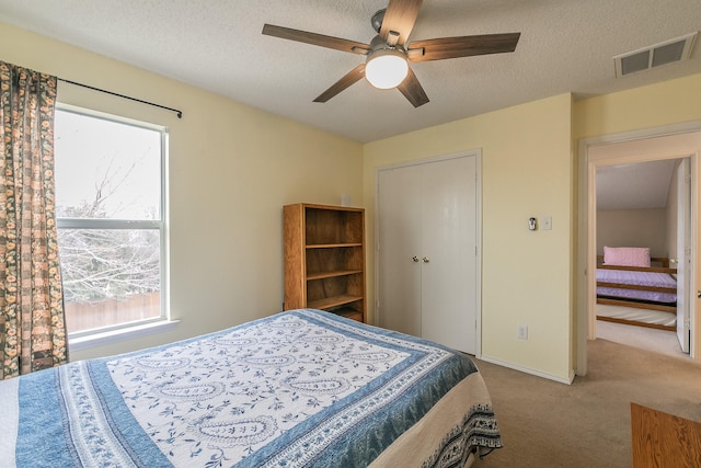 carpeted bedroom with a textured ceiling, a closet, and ceiling fan