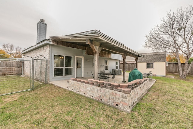 back of property with an outbuilding, a patio, and a lawn