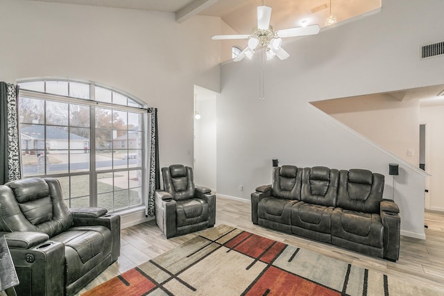 living room with ceiling fan, light hardwood / wood-style floors, beam ceiling, and high vaulted ceiling