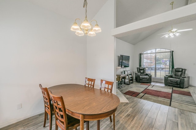 dining area with high vaulted ceiling and ceiling fan with notable chandelier