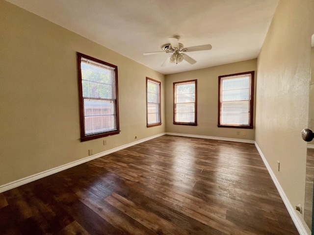 spare room featuring dark wood-type flooring, ceiling fan, and a healthy amount of sunlight