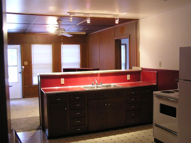 kitchen featuring ceiling fan, sink, fridge, electric stove, and wooden walls