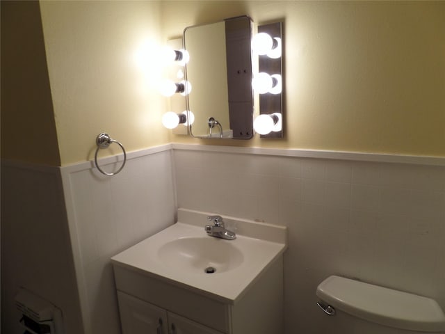 bathroom with vanity, toilet, and tile walls