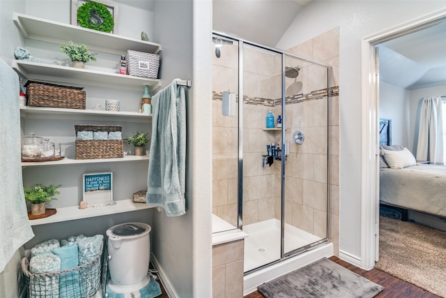 bathroom featuring hardwood / wood-style flooring, vaulted ceiling, and walk in shower