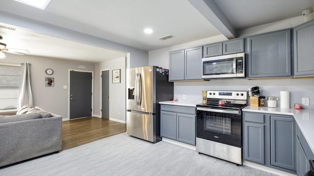 kitchen featuring gray cabinetry, light hardwood / wood-style flooring, ceiling fan, appliances with stainless steel finishes, and beam ceiling