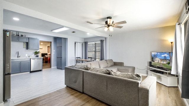 living room with ceiling fan, sink, and light hardwood / wood-style flooring