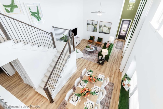 stairs with ceiling fan, a high ceiling, and hardwood / wood-style flooring