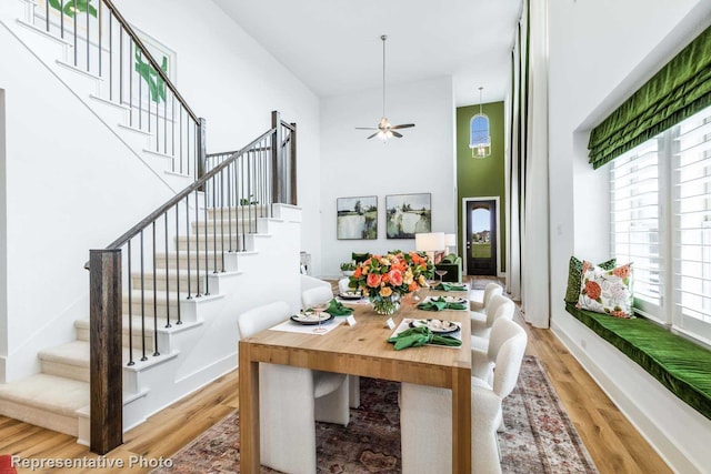 dining room featuring ceiling fan, a high ceiling, and light hardwood / wood-style flooring