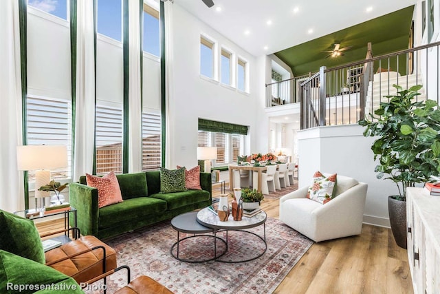 living room featuring ceiling fan, light hardwood / wood-style flooring, and a towering ceiling