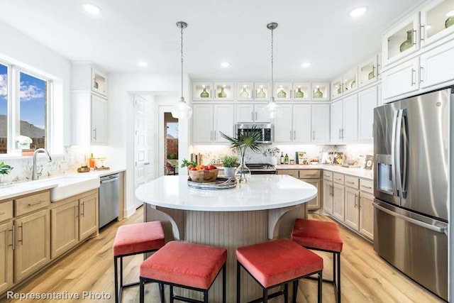 kitchen with white cabinetry, a center island, hanging light fixtures, stainless steel appliances, and a kitchen bar