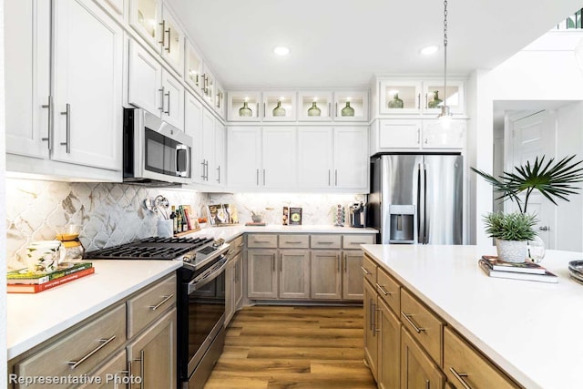 kitchen with dark hardwood / wood-style flooring, backsplash, pendant lighting, white cabinets, and appliances with stainless steel finishes