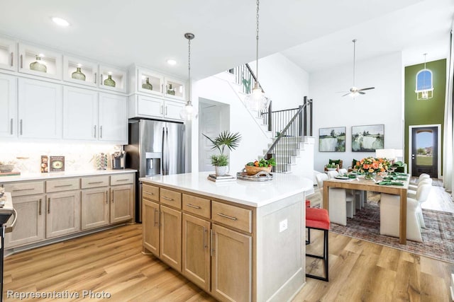 kitchen featuring a center island, hanging light fixtures, light wood-type flooring, light brown cabinetry, and white cabinetry