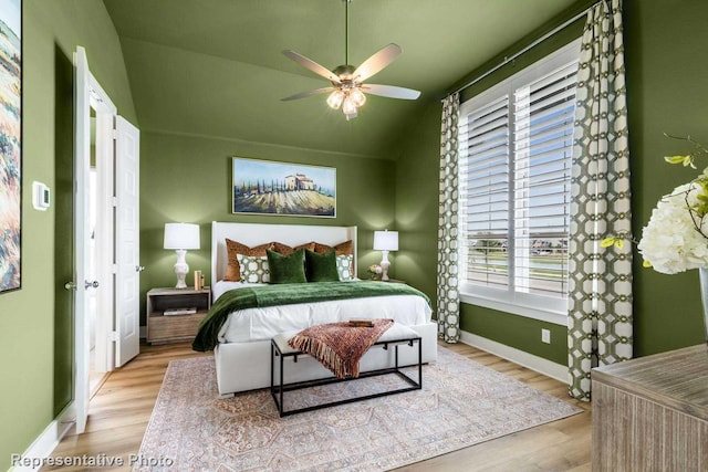 bedroom with multiple windows, light hardwood / wood-style flooring, ceiling fan, and lofted ceiling