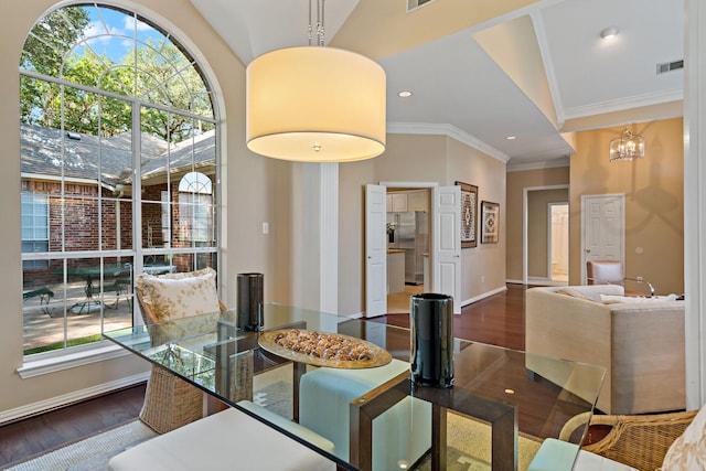 dining area with ornamental molding, hardwood / wood-style flooring, an inviting chandelier, and lofted ceiling