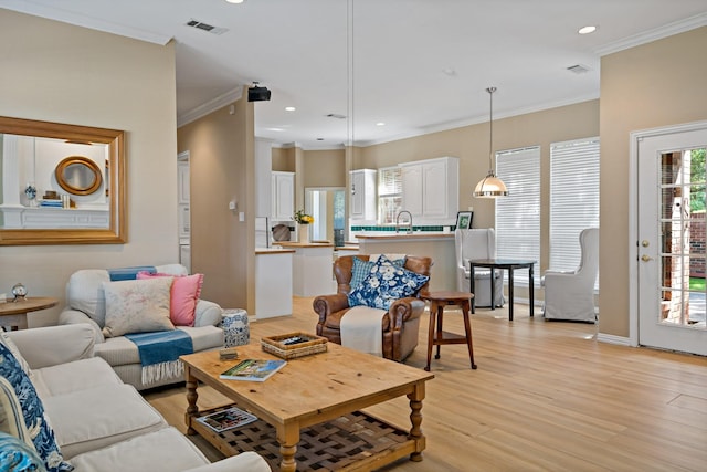 living room with crown molding, sink, and light hardwood / wood-style floors