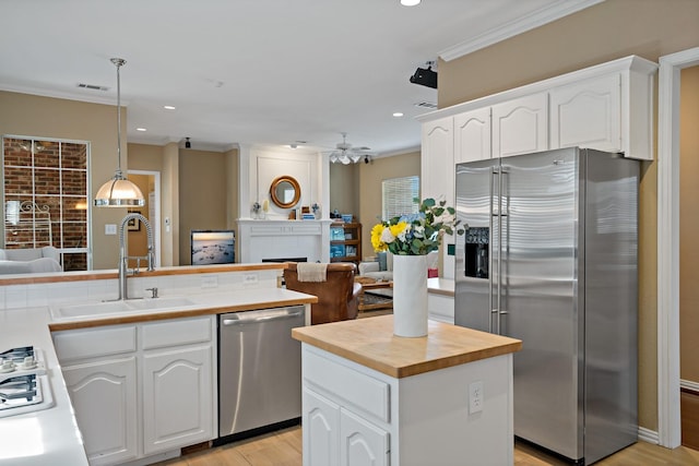 kitchen with stainless steel appliances, sink, pendant lighting, white cabinets, and a kitchen island