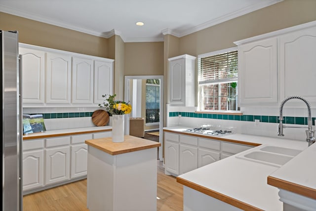 kitchen featuring white gas stovetop, sink, white cabinets, a center island, and stainless steel refrigerator