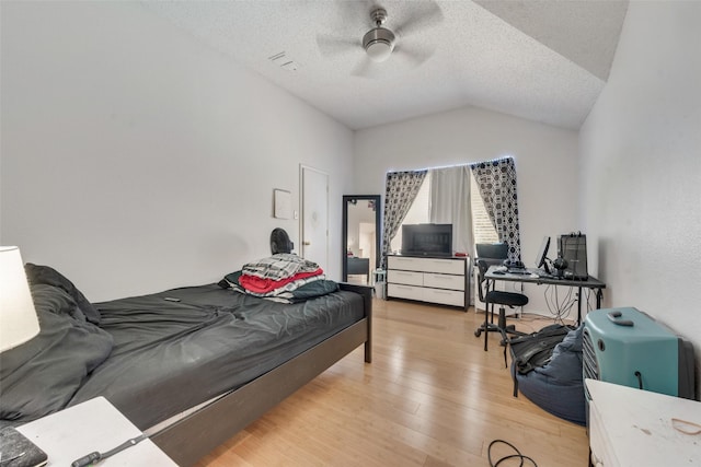 bedroom featuring ceiling fan, lofted ceiling, light hardwood / wood-style flooring, and a textured ceiling