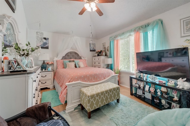 bedroom with ceiling fan, vaulted ceiling, light hardwood / wood-style floors, and a textured ceiling