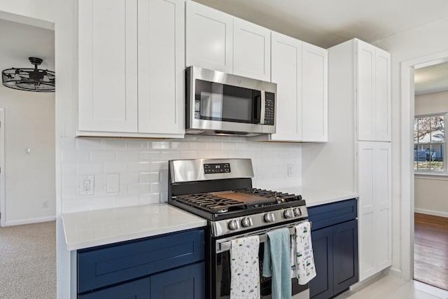 kitchen with light colored carpet, backsplash, blue cabinetry, white cabinets, and appliances with stainless steel finishes