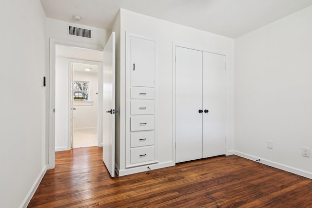 unfurnished bedroom featuring a closet and dark hardwood / wood-style floors