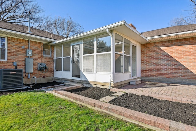 rear view of property with a lawn, cooling unit, and a sunroom