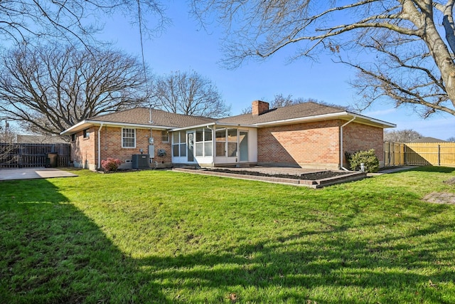 rear view of house with a patio, a lawn, and a sunroom