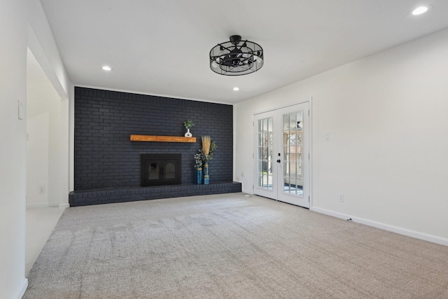 unfurnished living room featuring light colored carpet, french doors, and a fireplace