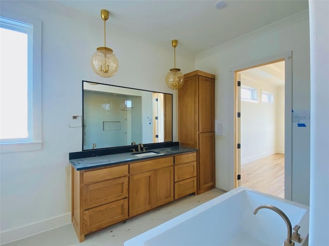 bathroom with a bathtub, vanity, a healthy amount of sunlight, and ornamental molding