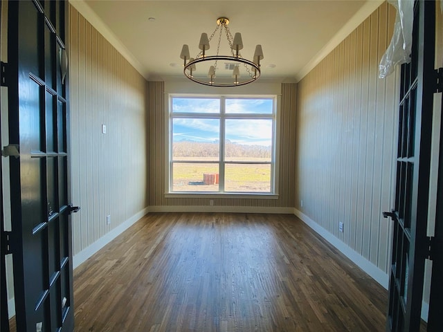 spare room with crown molding, dark hardwood / wood-style floors, and a notable chandelier