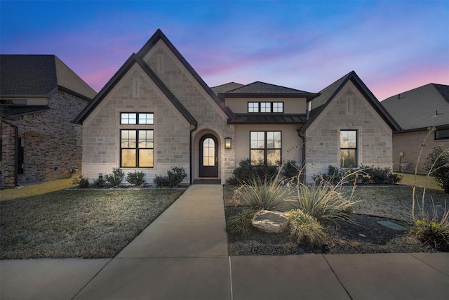 french country style house featuring stucco siding and a front lawn