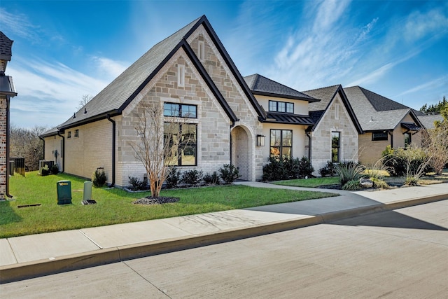 view of front of property featuring brick siding, a standing seam roof, metal roof, and a front yard