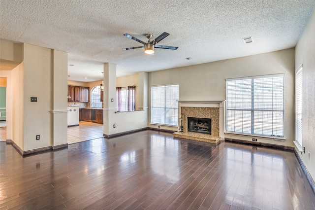 unfurnished living room with a fireplace, wood-type flooring, a textured ceiling, and ceiling fan