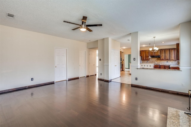 unfurnished living room with a textured ceiling, ceiling fan with notable chandelier, and light wood-type flooring