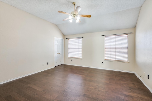 empty room with dark hardwood / wood-style flooring, lofted ceiling, and a wealth of natural light