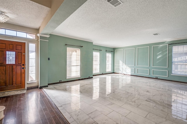 entryway with a textured ceiling and crown molding