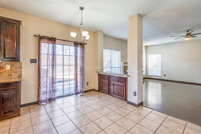 kitchen with light tile patterned floors, tasteful backsplash, light stone counters, and a wealth of natural light