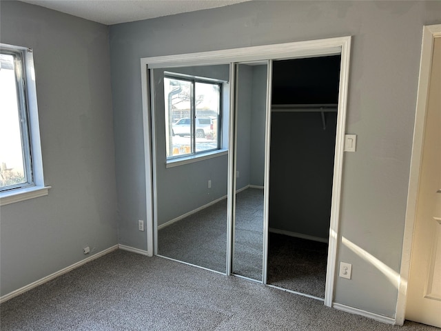 unfurnished bedroom with carpet flooring, multiple windows, and a closet