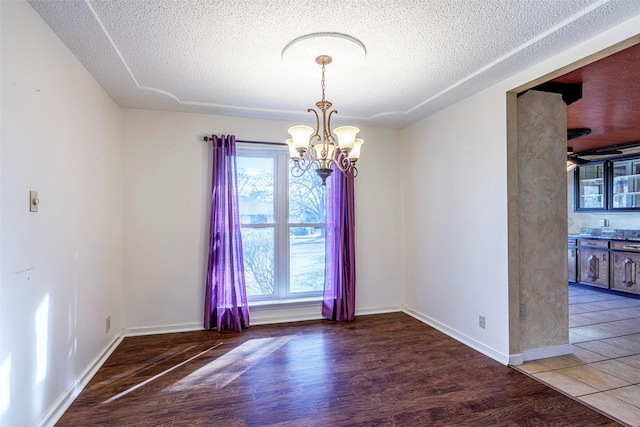 empty room featuring an inviting chandelier, hardwood / wood-style floors, and a textured ceiling