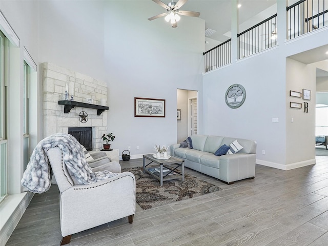 living room featuring a fireplace, a towering ceiling, hardwood / wood-style flooring, and ceiling fan