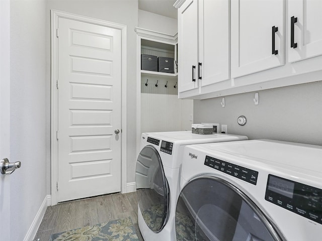 clothes washing area with washer and dryer, light hardwood / wood-style floors, and cabinets