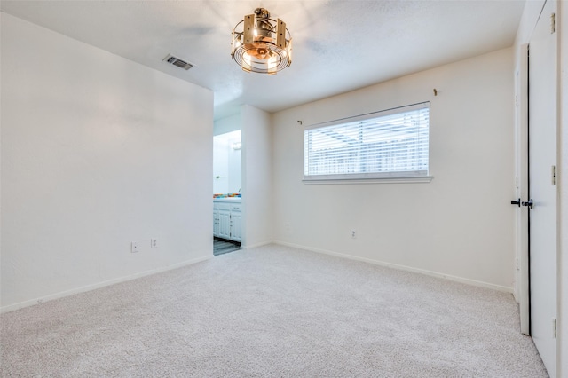 unfurnished bedroom featuring ensuite bath and light colored carpet