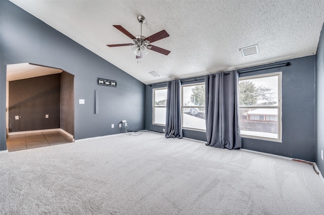 spare room featuring a textured ceiling, ceiling fan, light colored carpet, and vaulted ceiling