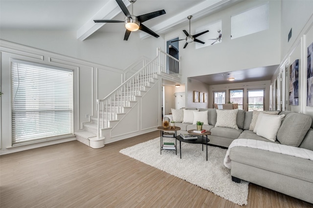 living room with beam ceiling, hardwood / wood-style flooring, high vaulted ceiling, and ceiling fan