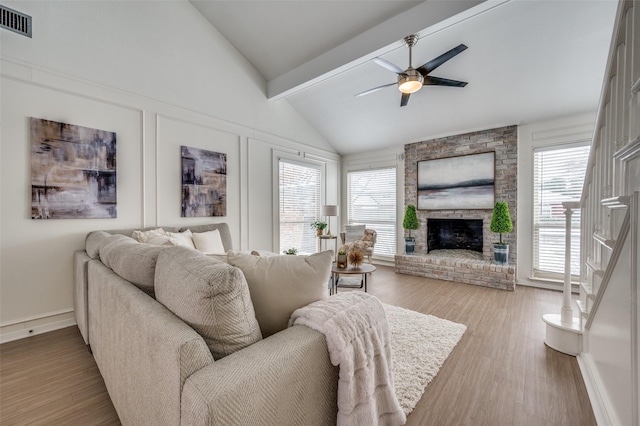 living room with a wealth of natural light, ceiling fan, light hardwood / wood-style floors, and a brick fireplace