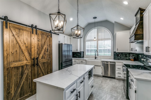 kitchen with pendant lighting, a center island, vaulted ceiling, a barn door, and appliances with stainless steel finishes