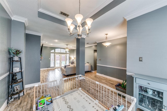 interior space featuring hardwood / wood-style flooring, french doors, ceiling fan with notable chandelier, and ornamental molding